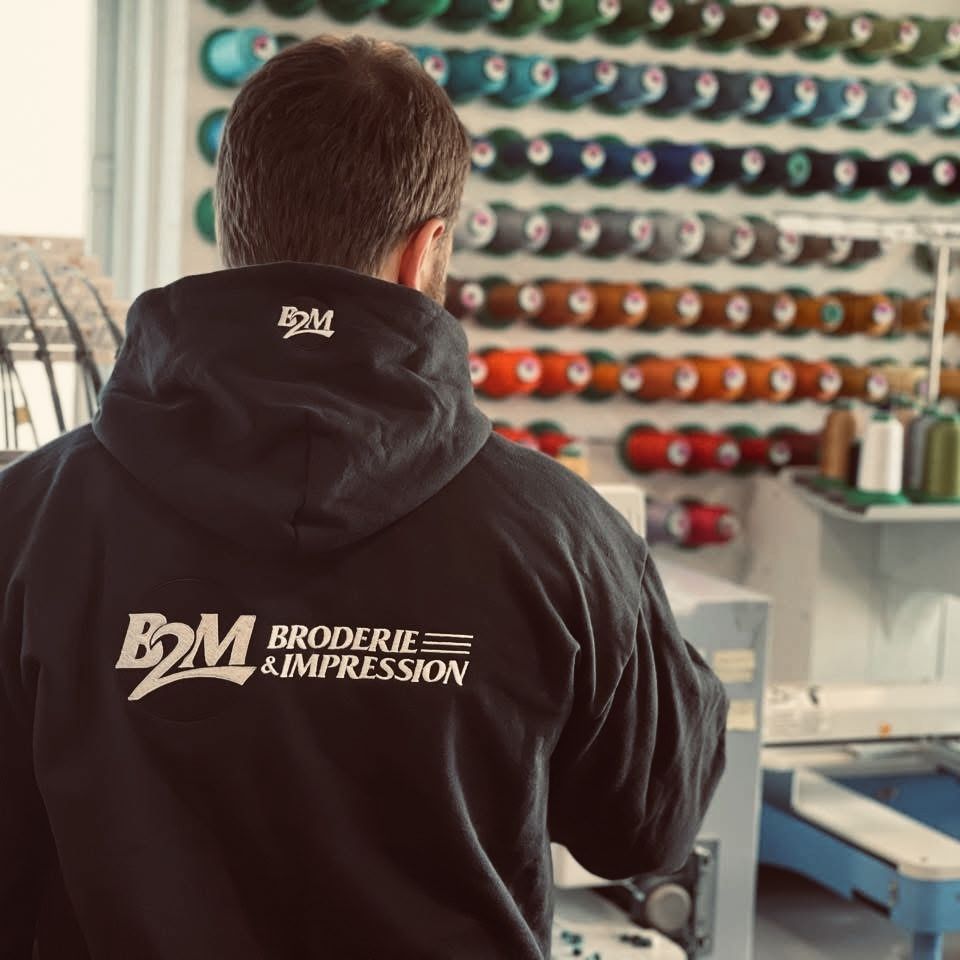 Broderie en cours devant le mur de cônes de fil, atelier B2M à Lévis